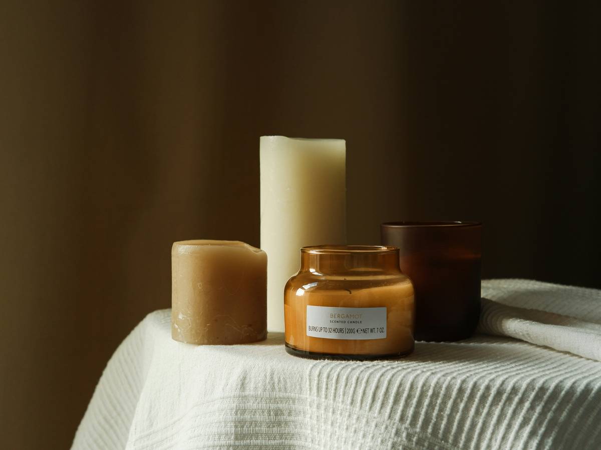 Infographic showing difference between essential oils vs fragrance oils in candle making, with temperature thresholds and therapeutic compound retention data